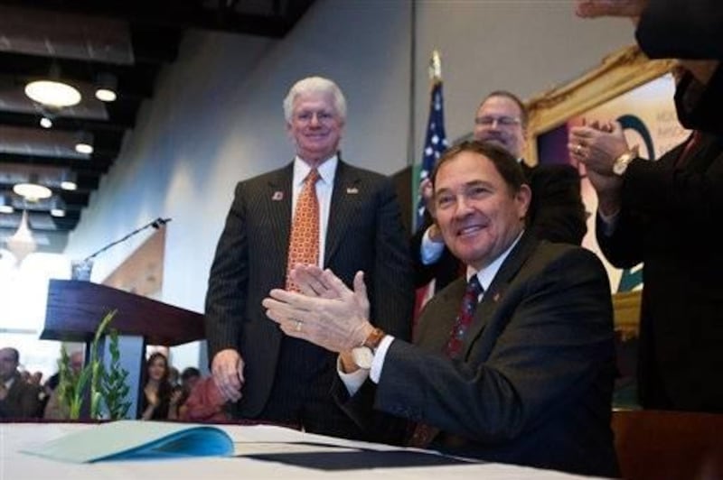 Utah Gov. Gary Herbert signs a bill into law transforming Dixie State College into a university inside the school's Eccles Fine Arts Center, in St. George, Utah on Saturday, Feb. 16, 2013.