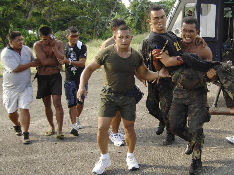 CORRECTS BYLINE - Wounded soldiers from Basilan province are assisted by their fellow troopers as they land at the southern port city of Zamboanga, Philippines, Tuesday, Oct. 18, 2011. Philippine troops are battling Muslim guerrillas in fierce fighting in