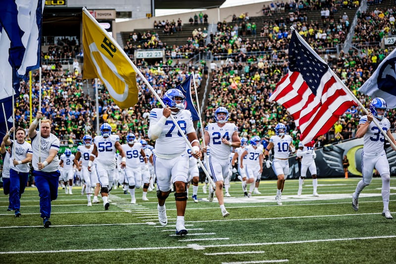BYU offensive lineman Kingsley Suamataia runs out an Oregon flag with Spencer Webb’s number on it prior to BYU’s game against Oregon at Autzen Stadium on Saturday, Sept. 17, 2022. Webb was killed in a hiking accident over the summer.