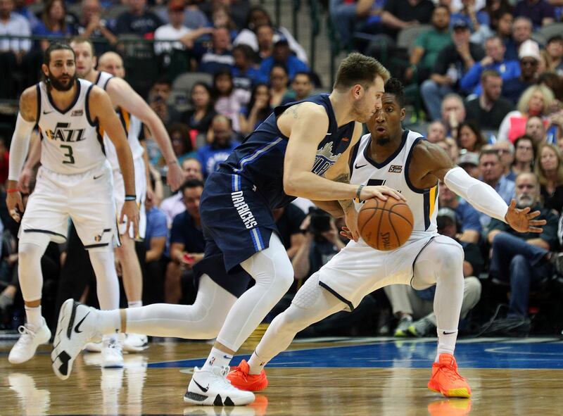 Dallas Mavericks forward Luka Doncic, wearing a blue jersey, tries to drive the ball past Utah Jazz guard Donovan Mitchell, wearing a white jersey, in the second half of an NBA basketball game Sunday, Oct. 28, 2018, in Dallas.