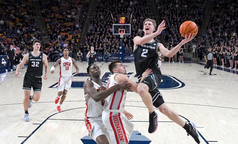 Utah State guard Sean Bairstow (wearing black) drives to the basket as UNLV forward Victor Iwuakor (0) and guard Jordan McCabe defend during the second half of an NCAA college basketball game Tuesday, Jan. 17, 2023, in Logan, Utah.