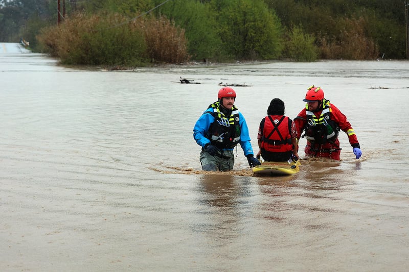 State Parks swift water technicians Jeremy Paiss and Bryan Kine transport Lizbeth Hernandez to safety after her truck was swept away by flood waters along Paulsen Road in Watsonville, Calif., Friday, March 10, 2023. Hernandez, who does not swim, stood on the roof of her truck for over an hour until Paiss and Kine could reach her and paddle her to safety.