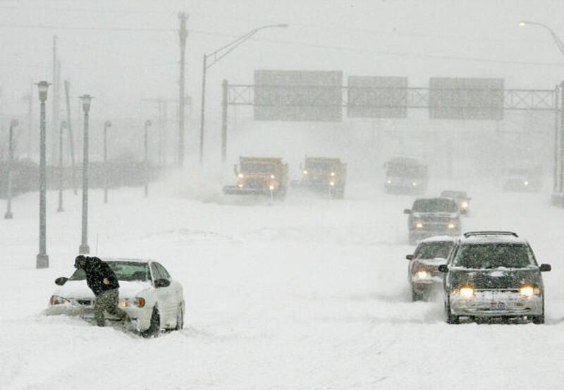 A stranded motorist tries to kick snow from in front of his car near Cleveland Hopkins Airport in Cleveland. Continental Airlines canceled two-thirds of its flights.