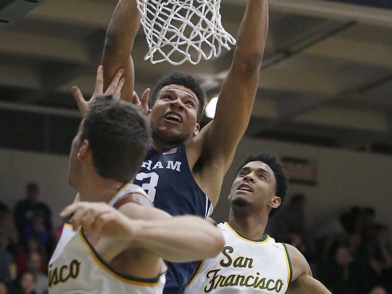 BYU forward Yoeli Childs, center, dunks between San Francisco center Jimbo Lull (5) and forward Nate Renfro (15) during the first half of an NCAA college basketball game Saturday, Feb. 11, 2017, in San Francisco. (AP Photo/Tony Avelar)