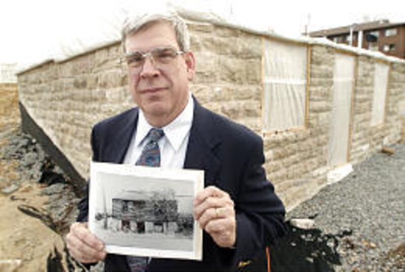 Henry Sweets, curator of the Mark Twain Museum in Hannibal, Mo., holds a photo of the original Blankenship House as he stands in front of what will be a replica. The original was destroyed in 1911. Tom Blankenship was a childhood friend of Samuel Clemens
