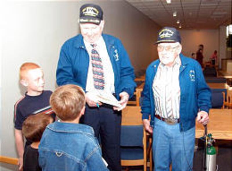 Woody James of Salt Lake City and Brian Blanthorn of Grouse Creek, both survivors of the sunken USS Indianapolis, sign books for Tyler Papiernik, 9, of Hyrum, left, Trevor Wood, 5, and his brother Thayne, 9.
