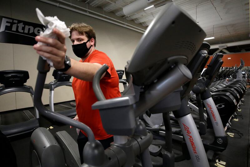 Mark Carbonaro, of Canton, Mass., cleans a piece of exercise equipment, Monday, July 6, 2020, before working out at the gym, in Canton.