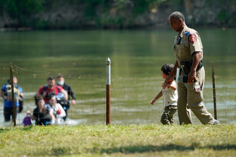 A Texas Department of Public Safety officer walks with a young boy after a group of migrants who crossed the border turned themselves in on June 16, 2021, in Del Rio, Texas.