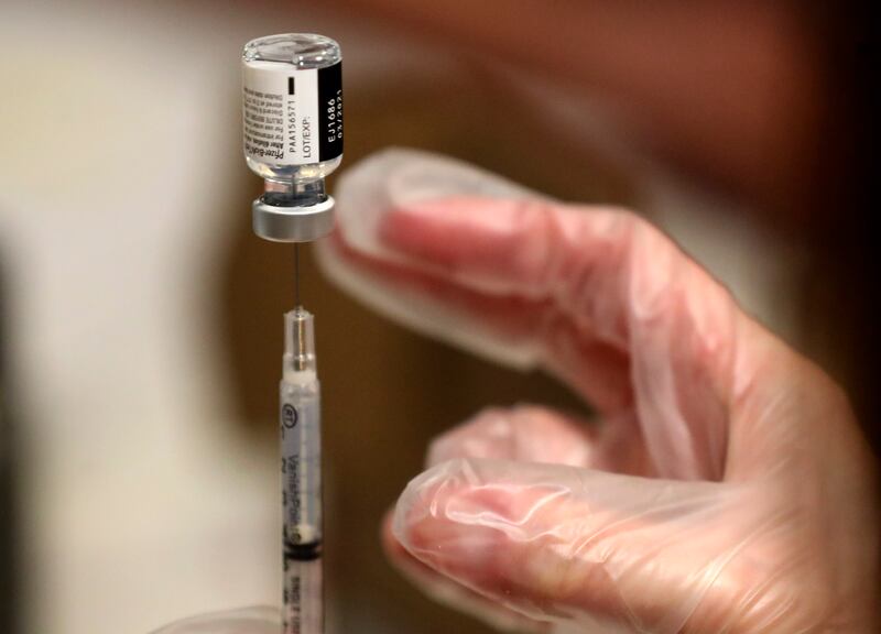 A pharmacist prepares a dose of COVID-19 vaccine.