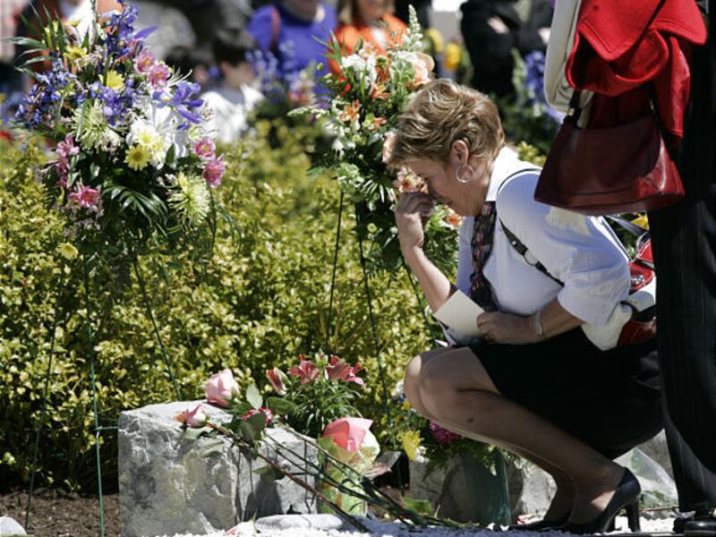 A family member wipes her face as she places a flower on a memorial marker at Virginia Tech.