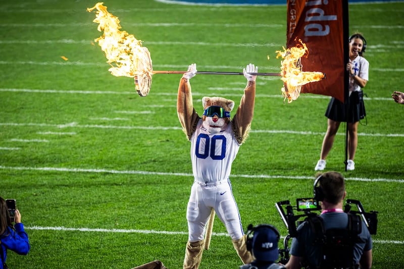 The BYU mascot Cosmo performs a backflip with flaming weights on a barbell on Sept. 21, 2024.