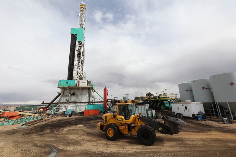 A worker operates a loader as a rig drills a well near Roosevelt, Utah.