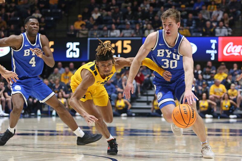 BYU guard Dallin Hall (30) is defended by West Virginia guard Noah Farrakhan, center, during the first half of an NCAA college basketball game Saturday, Feb. 3, 2024, in Morgantown, W.Va. (AP Photo/Kathleen Batten)