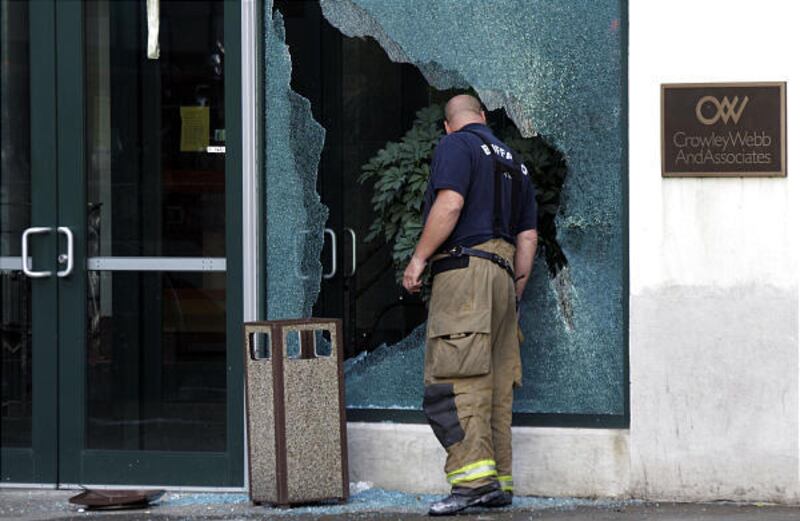 A firefighter looks through a broken window at the scene of a multiple fatal shooting near the City Grill bar and restaurant in Buffalo, N.Y.