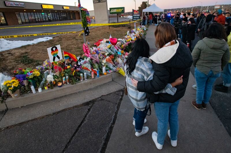 People gather around a memorial for the victims of Saturday’s fatal shooting at Club Q in Colorado Springs, Colo.