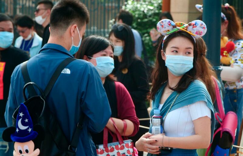Visitors, wearing face masks, wait to enter the Disneyland theme park in Shanghai.