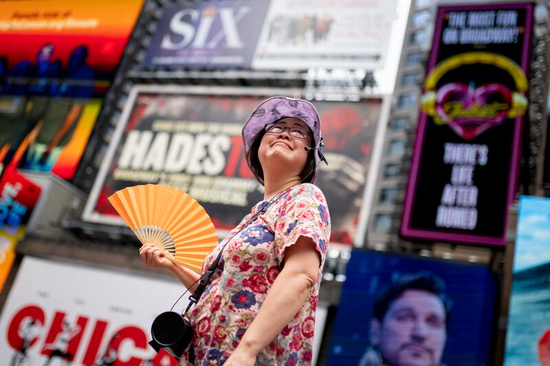 A tour guide fans herself while working in Times Square as temperatures rise in New York.
