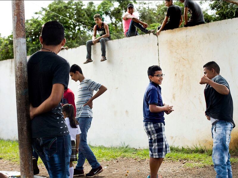 Patrick and his friends talk during recess as older boys watch them from a wall during Patrick's last day of school in Jerez, Guatemala, on Monday, Oct. 15, 2018.