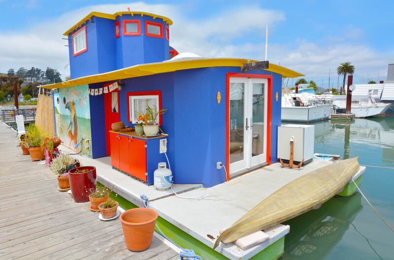 A colorful houseboat sits docked at a marina in San Fransisco.
