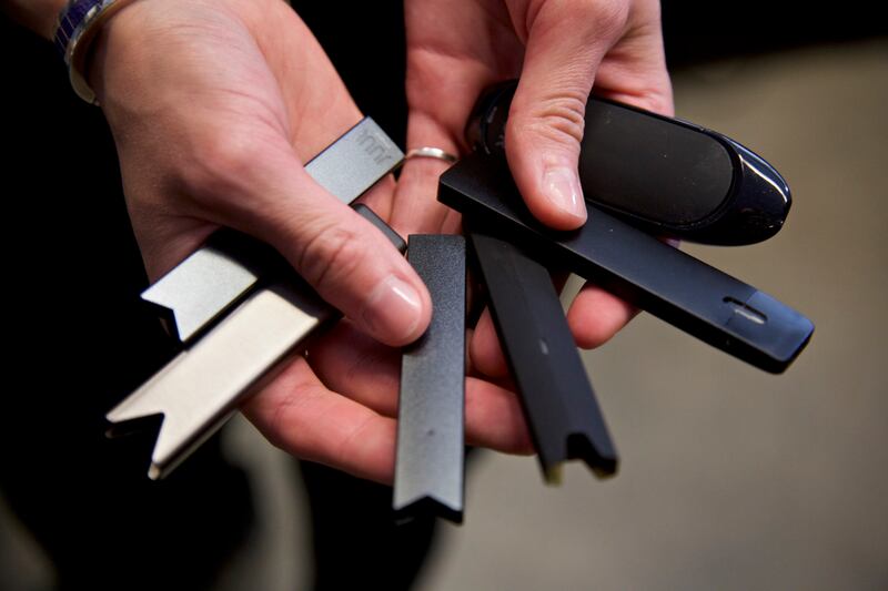 A researcher holds vape pens in a laboratory.