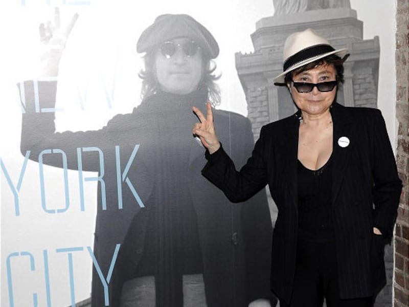 Yoko Ono poses in front of an image of the late John Lennon.