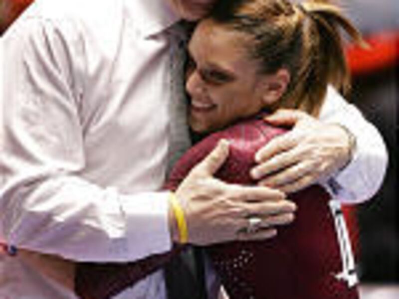 Alabama's Terin Humphrey gets a hug from coach David Patterson after competing on the bars in the individual event final of the NCAA Women's Gymnastics Championship at the Huntsman Center on Saturday night.