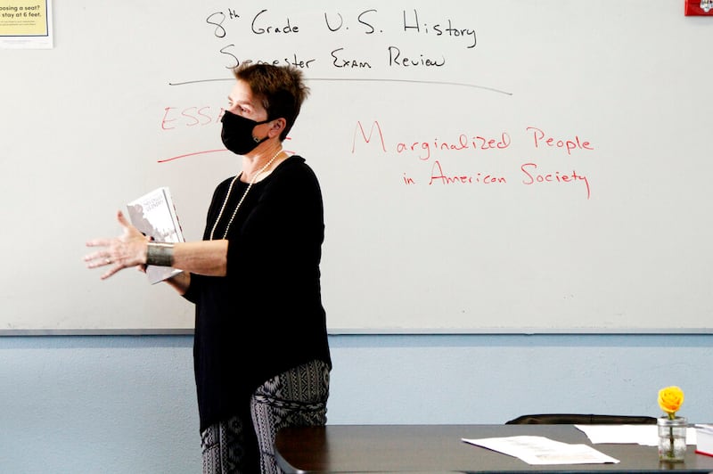 History teacher Wendy Leighton holds a copy of “They Called us Enemy” at Monte del Sol Charter School in Santa Fe, N.M.