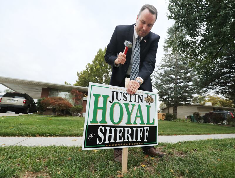 Justin Hoyal, a candidate for Salt Lake County sheriff, posts a sign as he campaigns in Murray on Wednesday, Oct 10, 2018.