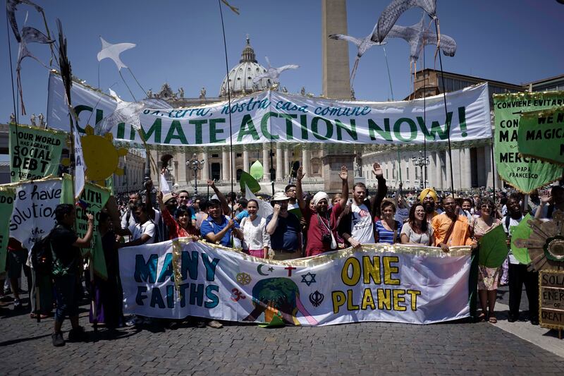 People hold banners reading ‘Climate action Now’ and ‘Many Faiths, One Planet’ in St. Peter’s Square, at the Vatican, Sunday, June 28, 2015. Marchers included Christians, Muslims, Jews, Hindus and others.