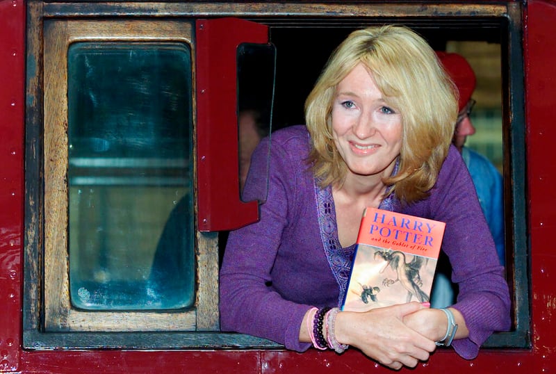 Author J.K. Rowling leans out of a steam train.