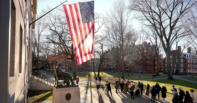 People take photos near a John Harvard statue, left, on the Harvard University campus, Jan. 2, 2024, in Cambridge, Mass.