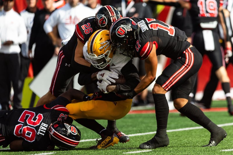 Arizona State Sun Devils wide receiver Elijhah Badger is tackled by Utah’s Johnathan Hall, left, Charlie Vincent and Smith Snowden, right, wearing black.