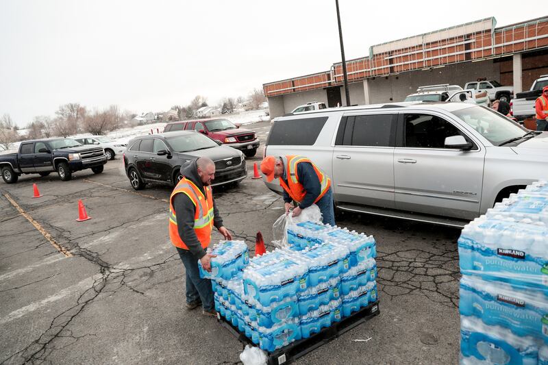 Sandy city employees Taylor Vick and Mike Fox distribute water to residents at a staging area on 700 East in Sandy on Saturday, Feb. 16, 2019. Residents in a portion of the city have been instructed not to use their tap water due to contamination from exc