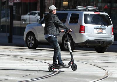 An e-scooter renter rides over TRAX rails on Main Street in Salt Lake City on Friday, April 19, 2019.