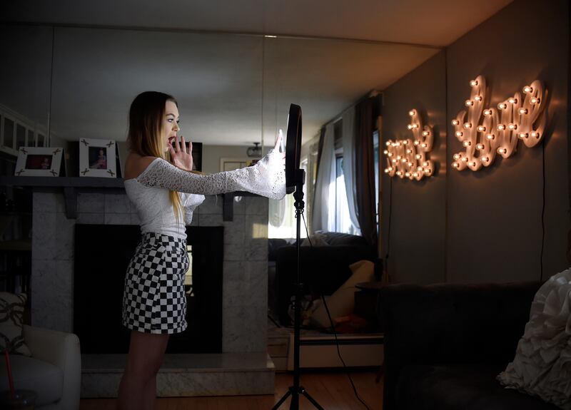 In this Feb. 28, 2018 photo, Matty Nev Luby holds up her phone in front of a ring light she uses to lip-sync with the smartphone app TikTok