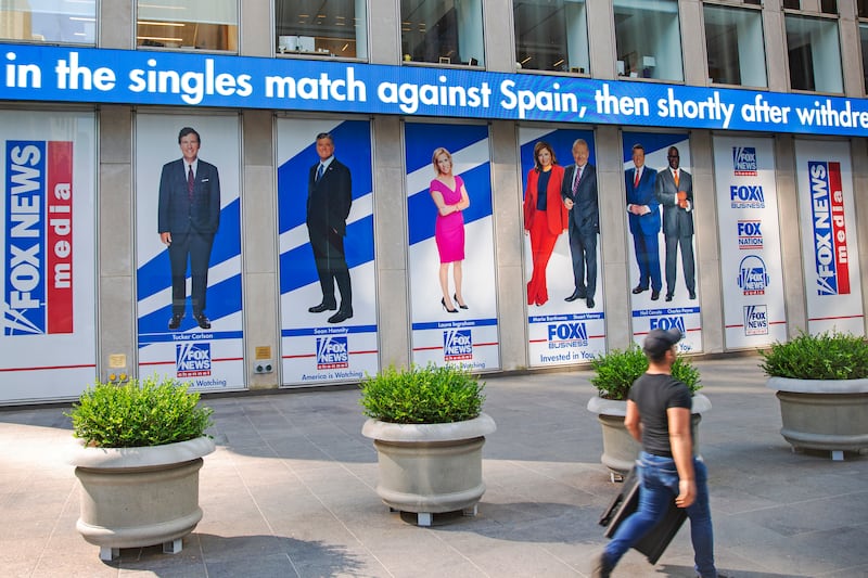 A man walks past promotional posters outside Fox News studios at News Corporation headquarters in New York on July 31, 2021.