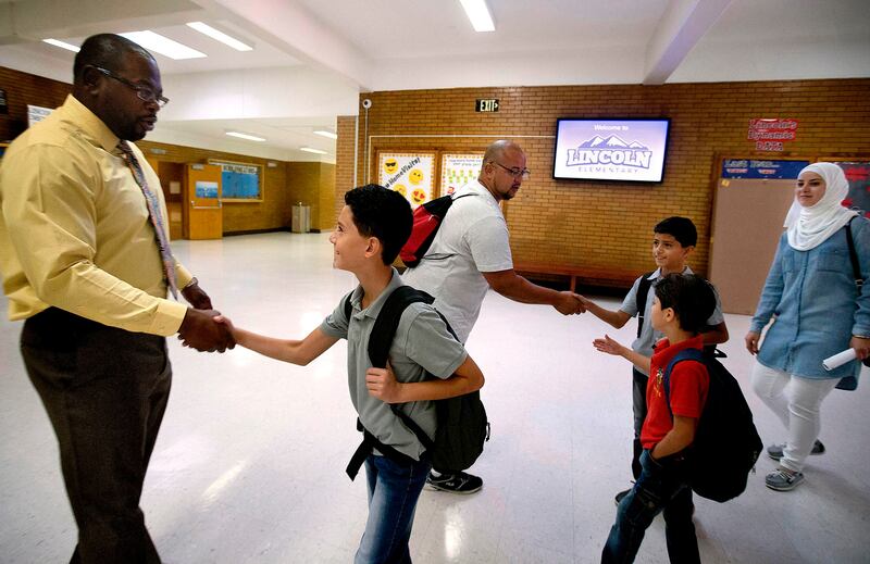 Lincoln Elementary School Principal Milton Collins, left, and coach Eddie Berrest greet the Hamad boys and their mother on their first day of school at Lincoln in Salt Lake City on Thursday, Sept. 7, 2017.