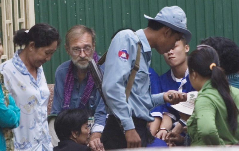 German Karl Heinz Henning, 61, second left, sits outside the court room in the capital Phnom Penh, Cambodia, Friday, March 9, 2007. The court on Friday sentenced Henning to 28 years in prison on human trafficking and sexual abuse of four Vietnamese girls