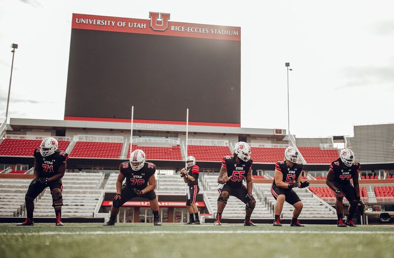 Utah quarterback Cam Rising and the offensive line, wearing white helmets, black jerseys and black pants, provide a look at Utah’s uniform combination