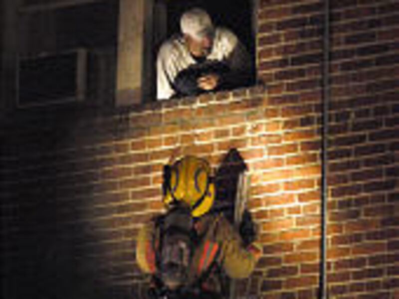A firefighter urges a man in a third-floor room to climb down a ladder during the Mizpah Hotel fire Tuesday. Six people died in the fire.