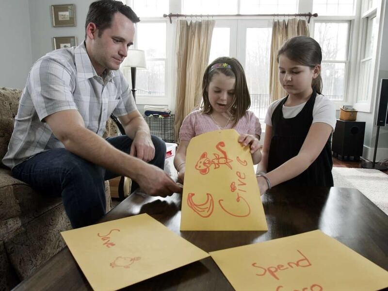 Kevin McLaughlin watches as 8-year-old daughter Chloe McLaughlin and her friend Caleigh Everitt, 9, right, count some of the allowance money Chloe keeps in different envelopes, at the McLaughlin home in Pine Beach, N.J., Friday, March 27, 2009. One envelo