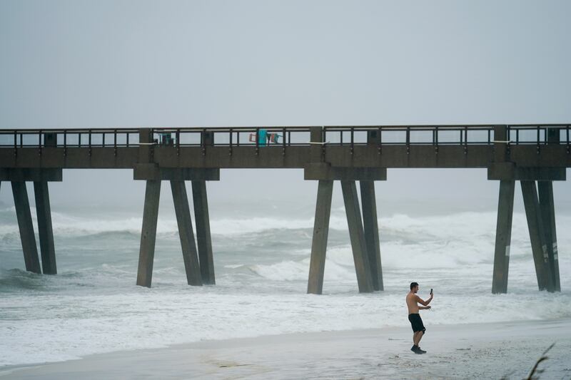 A person takes a photo at Navarre Beach, Tuesday, Sept. 15, 2020, in Pensacola Beach, Fla. Hurricane Sally is crawling toward the northern Gulf Coast at just 2 mph, a pace that’s enabling the storm to gather huge amounts of water to eventually dump on land.