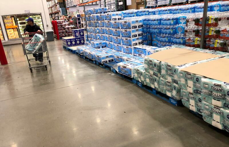 A shopper pushes a cart past a dwindling supply of toilet paper and hand towels in a Costco warehouse as shoppers continue to buy paper products in response to the spread of the coronavirus Monday, March 23, 2020, in Lone Tree, Colo. (AP Photo/David Zalubowski)