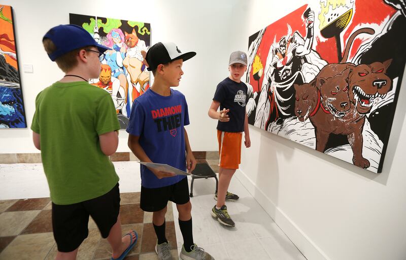 Will Jurgens, Gabe Leaviitt and Sam Jurgens talk about who is going to paint what as parents and kids enjoy coloring the different art pieces at the Woodbury Art Museum's "Heroes and Villains: How Mythology Made Comics" exhibition at University Mall in Or