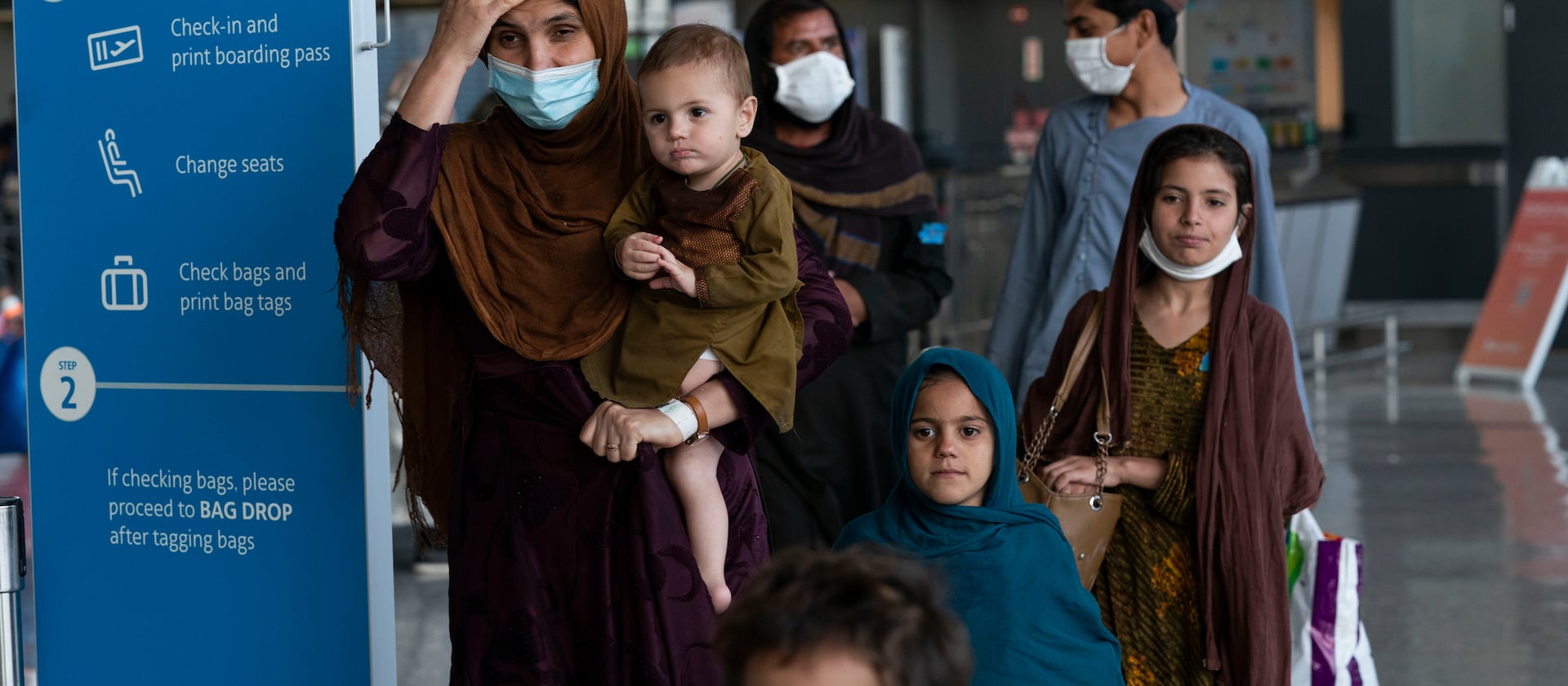 Families evacuated from Kabul, Afghanistan, walk through a terminal upon arrival at Washington Dulles International Airport.