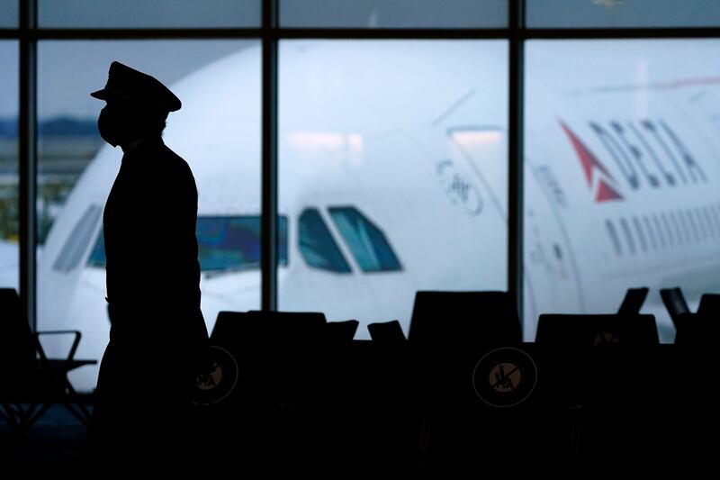 A Delta Airlines pilot wears a face mask as he walks through a terminal at Hartsfield-Jackson International Airport.