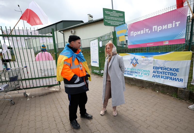 Volunteer Sasha wears a Ukrainian flag while talking with Anzhela Kumurxhi, a Ukrainian refugee from Mariupol, at the Ukrainian-Polish border in Medyka, Poland.