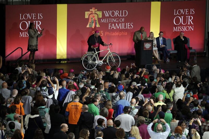 Philadelphia Mayor Michael Nutter, at podium, speaks about a bicycle being examined by Archbishop of Philadelphia Charles Chaput, that the city plans to give to Pope Francis, during a ceremony marking the opening of the World Meeting of Families, Tuesday,