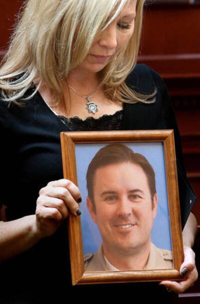 FILE: Nannette Wride holds a photo of her husband, Sgt. Cory Wride, while he is honored at the Capitol on Wednesday, March 12, 2014.