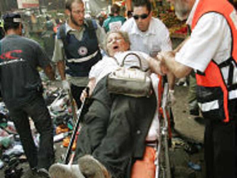 A survivor is evacuated from the site of Monday's blast in Carmel market in Tel Aviv. Three Israelis were killed; 32 wounded.